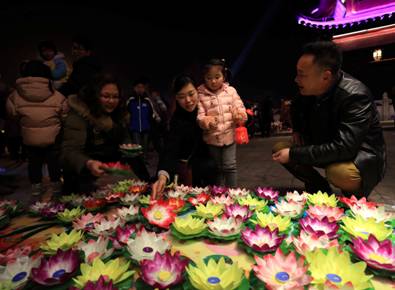 2月28日，在安徽省全椒县太平桥上，一位家长在为小朋友选购荷花灯。